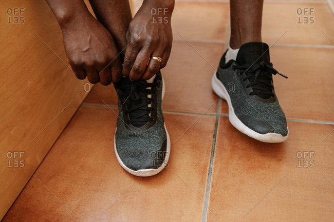 Close up top view of black woman`s hands tying shoelaces on sneakers in the house