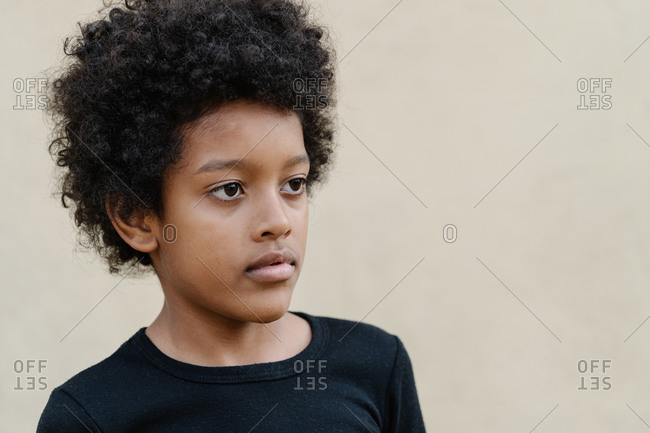 Portrait of serious afro boy in black shirt on beige background