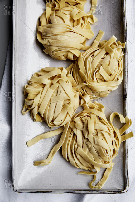 A close up of bunches of fresh, handmade raw pasta on a plate,