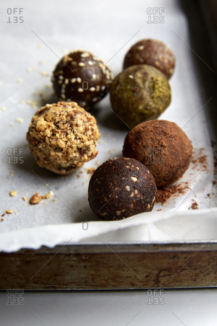 Different types of date balls laid out on wax paper in a baking tin,