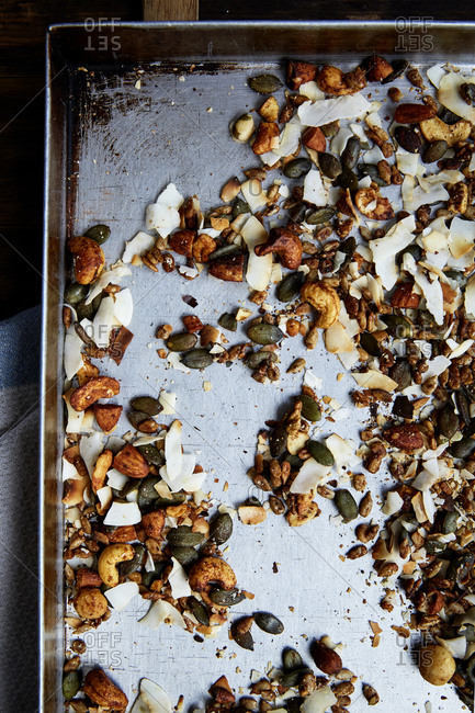 Seed, nut and coconut flake granola in a baking tray straight out of the oven,