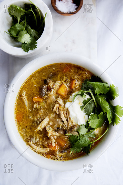 Immune boosting chicken soup with a spoonful of yoghurt and fresh herbs on a light background,