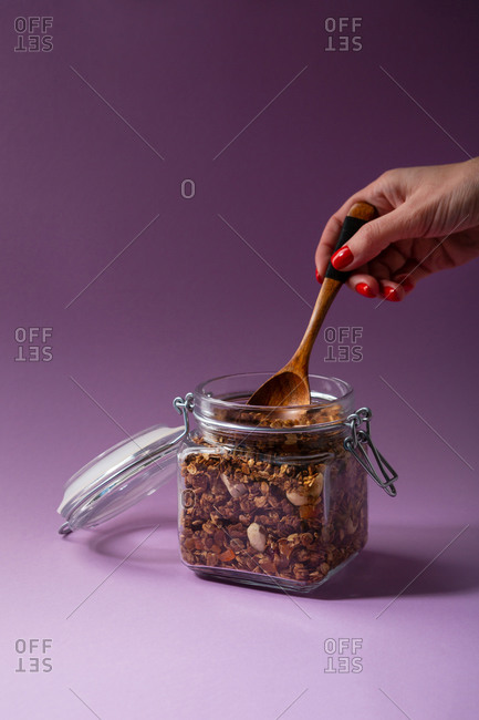Scooping homemade granola from a jar