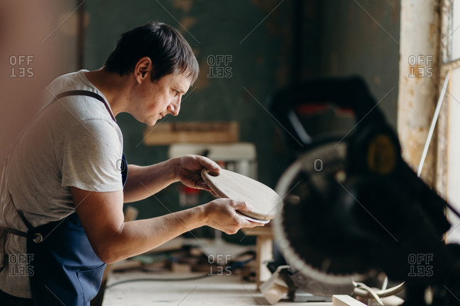A carpenter touching and inspecting wooden board in a workshop. Process of creating a wooden furniture.