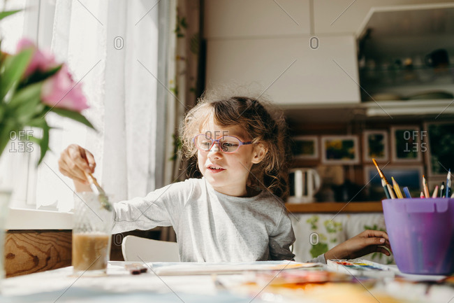 Cute little girl in glasses drawing a picture at home. Home education concept