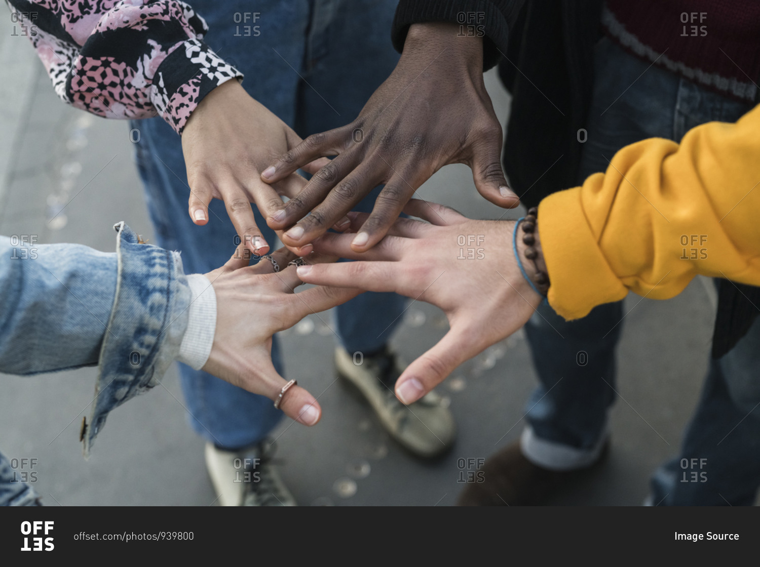 Four female and male young adult friends bringing hands together, close up of hands