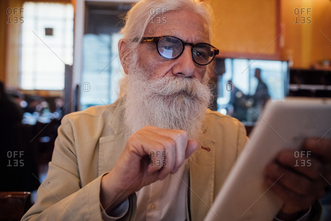 Senior businessman using digital tablet in cafe