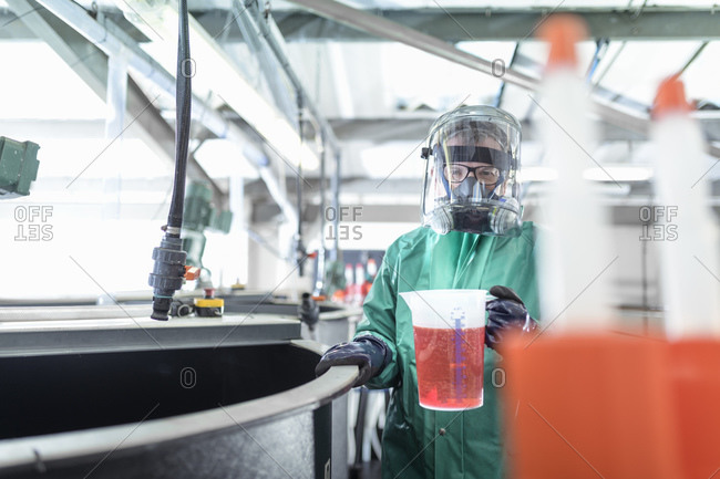 Worker with jug of chemical in chemical factory