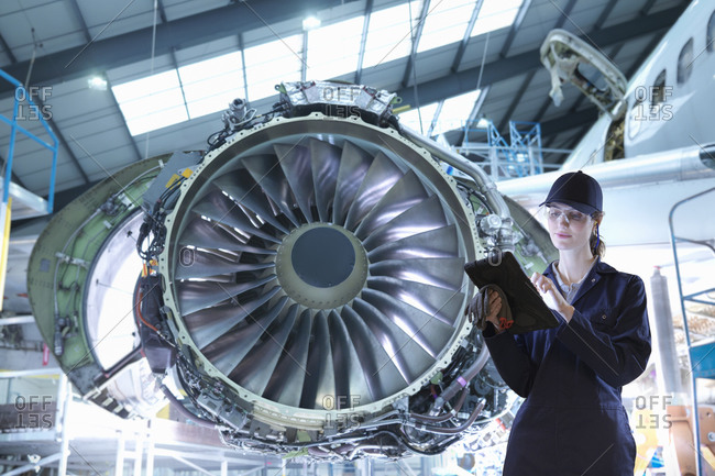 Composite image of female worker with digital tablet in aircraft maintenance factory