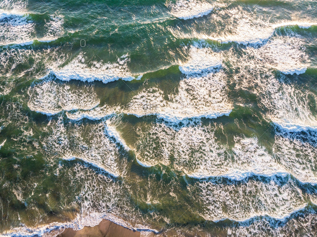 Aerial view of ocean waves crashing on beach.