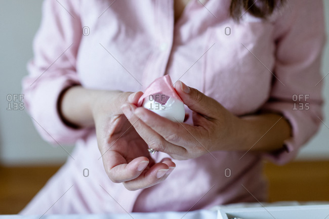 Cropped view lady holding an egg ad covering with pink paper