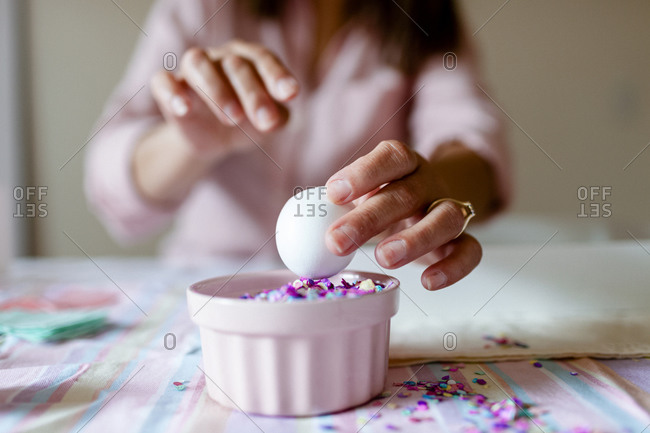 Cropped view lady filling eggs with colorful confetti