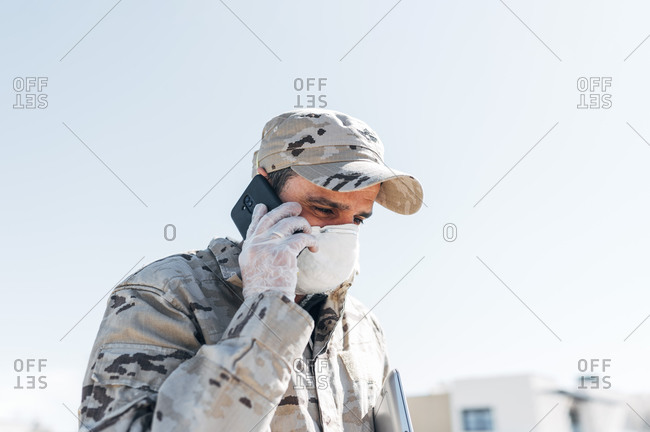 Soldier with face mask on emergency operation- using smartphone