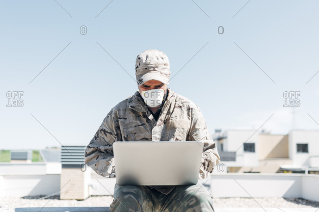 Soldier with face mask on emergency operation- using laptop