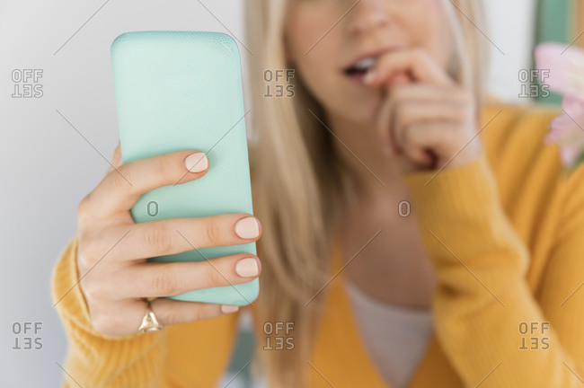 Woman holding smartphone and biting nails