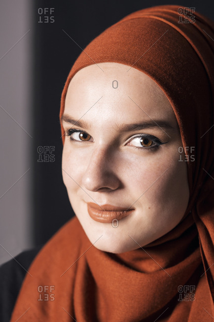 Portrait of a young adult Muslim female wearing brick orange hijab, looking to camera