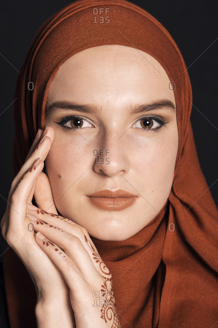 Portrait of a young adult Muslim female wearing brick orange hijab, looking serious close up