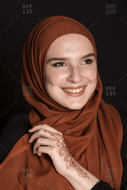Portrait of a young adult Muslim female wearing brick orange hijab, looking serious
