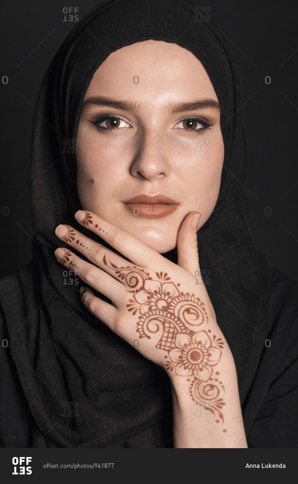 Portrait of a young adult Muslim female wearing black hijab, henna