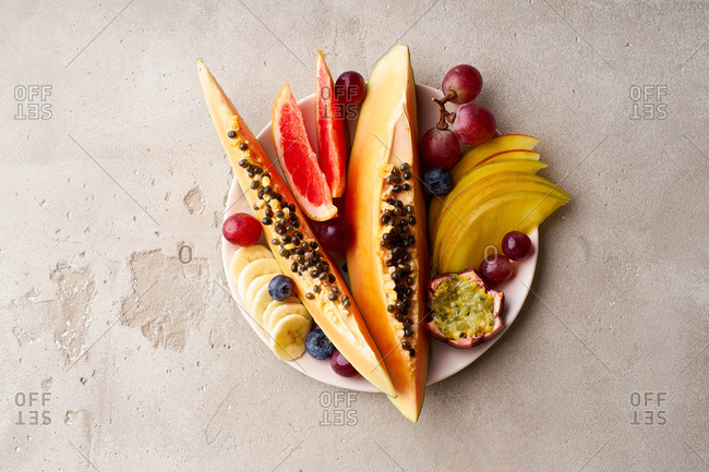 Colorful tropical summer fruits and berries. Papaya, mango, passion fruit, banana, grapes sliced and served on a plate. Summer fruits platter