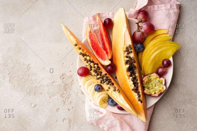Colorful tropical summer fruits and berries. Papaya, mango, passion fruit, banana, grapes sliced and served on a plate. Summer fruits platter