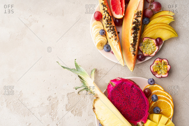 Colorful tropical summer fruits and berries. Papaya, mango, passion fruit, banana, grapes sliced and served on a plate. Summer fruits platter