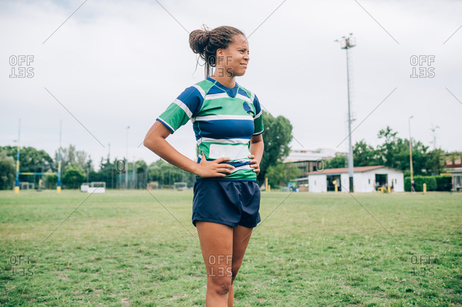 A woman wearing a blue, white and green rugby shirt standing on a training pitch.