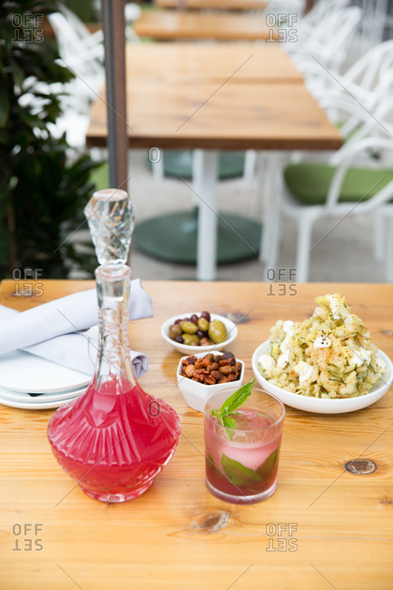 Pink cocktail and snacks on wooden table