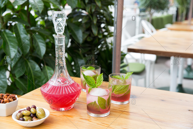 Pink cocktail on a wooden table with snacks