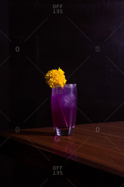 Purple cocktail with a large yellow flower