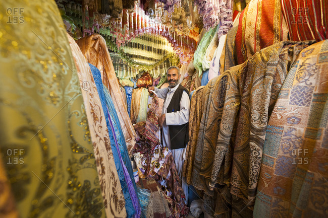 Kabul, Afghanistan - June 11, 2011: A man standing among a jumble of colors at a fabric bazaar