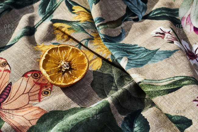 Half rotten orange on a wrinkled floral-patterned fabric