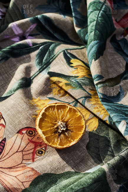 Half rotten orange on a wrinkled floral-patterned fabric