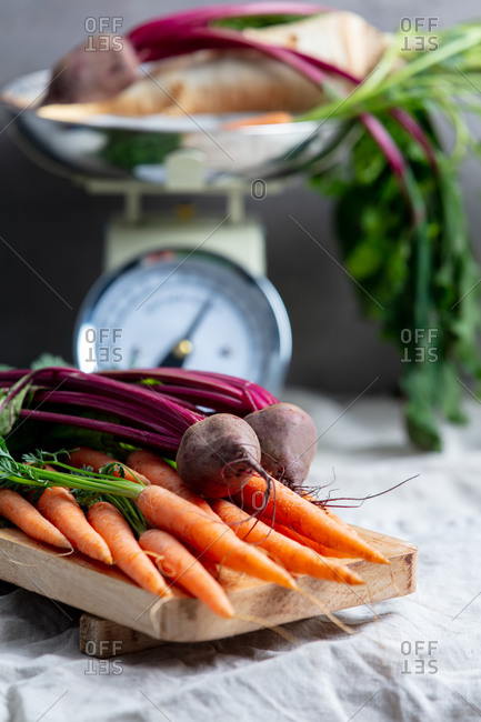 Carrots, beets and vintage scale on background