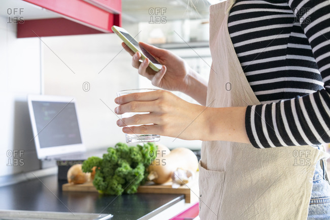 Young woman preparing healthy meal- using smartphone