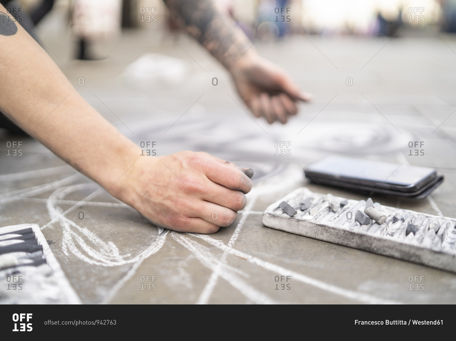 Street art- pavement artist drawing on pavement and using smartphone