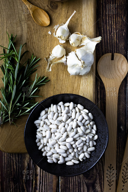 Cutting board- wooden ladle and spoon- garlic- rosemary and bowl of white beans
