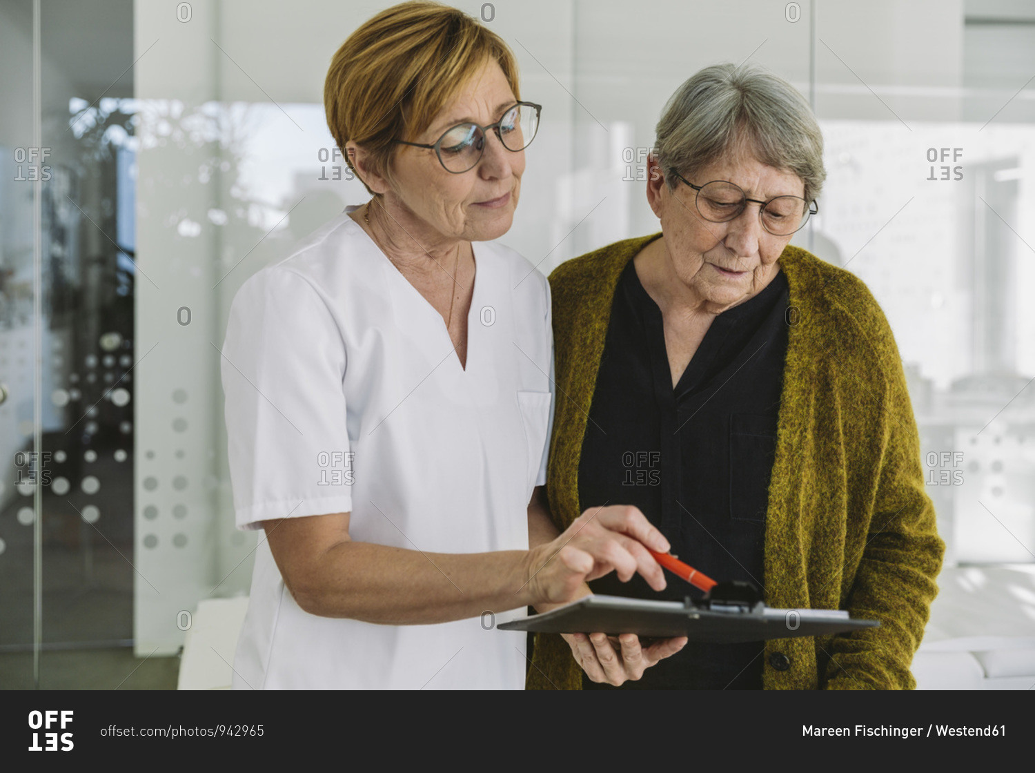 Medical secretary helping senior patient filling out document