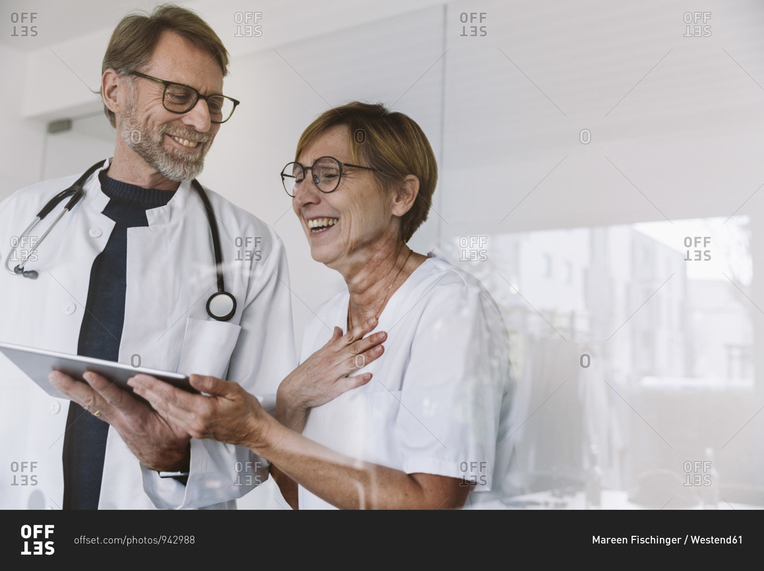 Happy doctor and assistant using tablet in medical practice