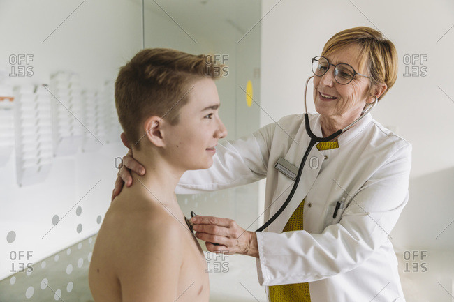 Doctor examining teenage boy with a stethoscope