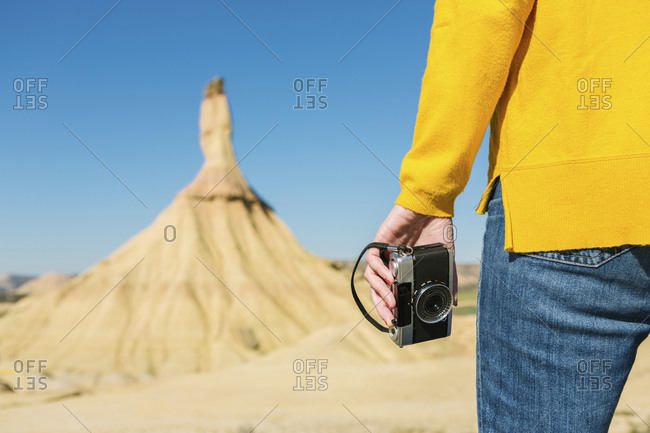 Woman holding a vintage camera in desertic landscape of Bardenas Reales- Arguedas- Navarra- Spain
