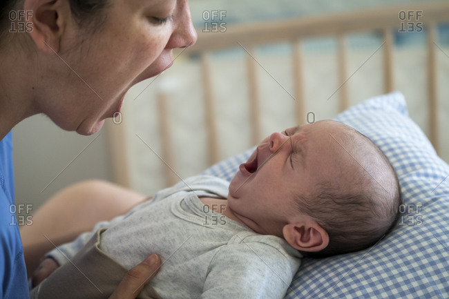 Mother with mouth open imitating yawning baby at home