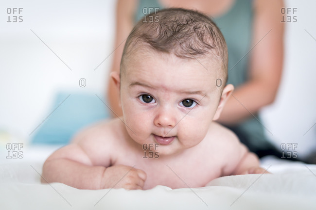 Close-up portrait of cute baby boy with brown eyes lying on bed