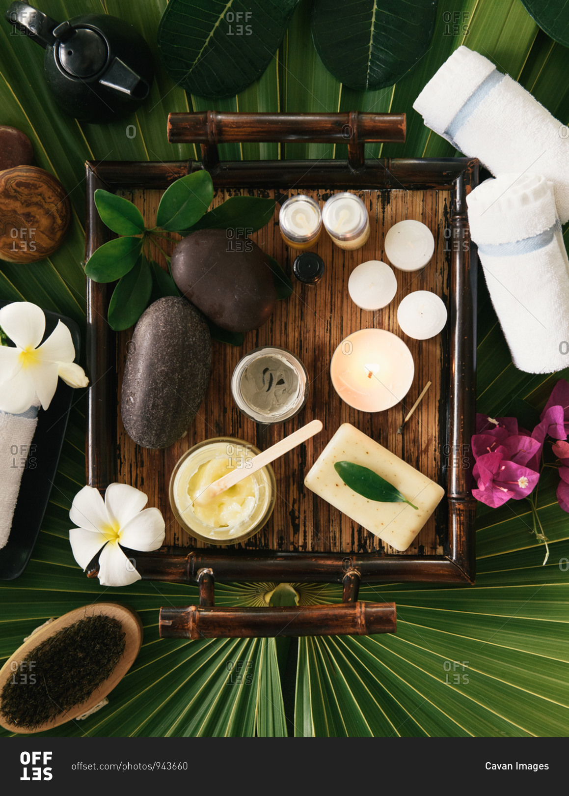 Overhead of spa kit with candles and scrubs and rubs on palm frond
