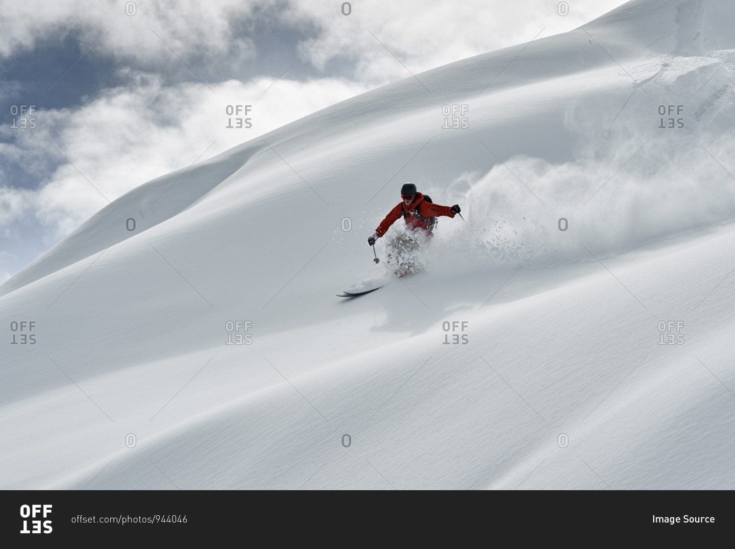 Male skier skiing down snow covered mountain, Alpe-d'Huez, Rhone-Alpes, France