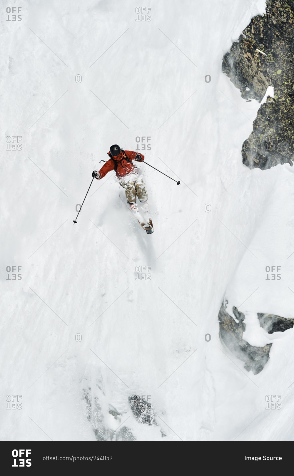 Male skier skiing down vertical mountainside, Alpe-d'Huez, Rhone-Alpes, France