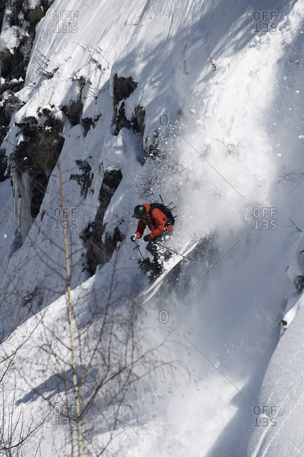 Male skier speeding down rugged vertical mountainside, Alpe-d'Huez, Rhone-Alpes, France