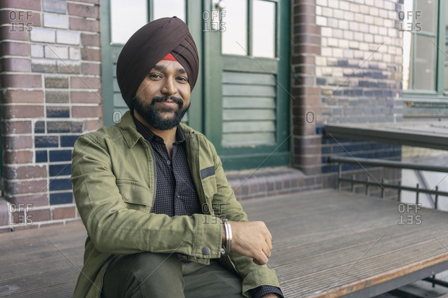 Indian man in front of building with brick wall, Berlin, Germany