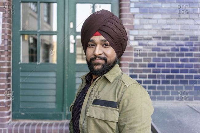 Indian man in front of building with brick wall, Berlin, Germany