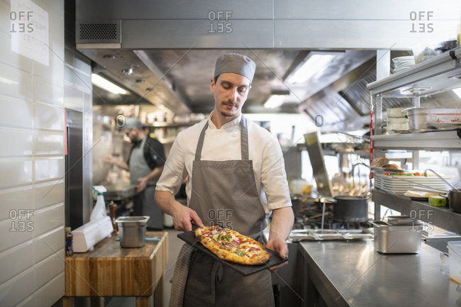 Chef in kitchen holding a Pinsa Romana, a Roman style pizza blend reducing sugar and saturated fat, containing rice and soy with less gluten